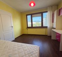 Yellow walls of the room with a wood-patterned floor in a 3-room apartment.