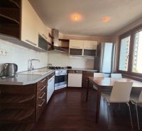 A kitchen in a 3-room apartment with a wooden decor floor and a dining table.