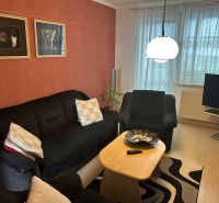Living room in a three-room apartment with a sofa, table, and wall decorations.