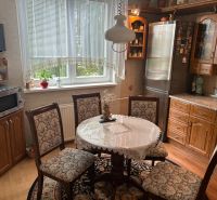 A kitchen in a 3-room apartment with a wooden decor floor and a lace tablecloth on the table.