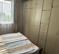 Bedroom in a 3-room apartment with built-in wardrobes and an open window to a green environment.