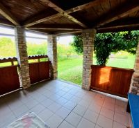 Stone pillars and wooden railing on the terrace of the cottage in Podhorany near the meadow.