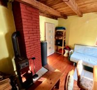 Interior of a cabin with a fireplace, sofa, and wooden decor flooring.