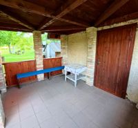 A wooden gazebo at the cottage in Podhorany with brick walls and garden furniture.
