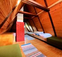 The attic of the cottage with a wooden decor floor and simple beds.