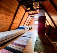 A wooden interior of a cabin with a bed and a carpet on the floor with a wooden decor.