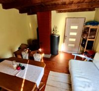 Living area in a cottage with a wooden decor floor, a sofa, and a table.