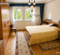 Bedroom with wood-patterned flooring, yellow bedspread, and large windows in a family house.