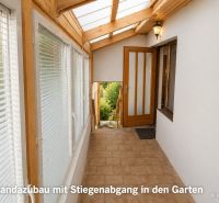 A veranda with a glass roof and staircase in a family house.