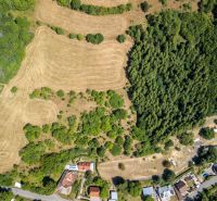 Aerial view of a plot in Banská Štiavnica on Obrancov Mieru Street with forests and houses.