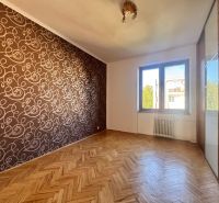 A room in a 4-room apartment with a wooden decor floor and patterned wallpaper.