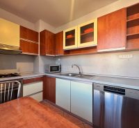 A kitchen in a 4-room apartment with a dishwasher and a kitchen unit with a wooden decor.