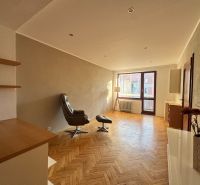 Living room in a four-room apartment with a wooden decor floor and a comfortable armchair.