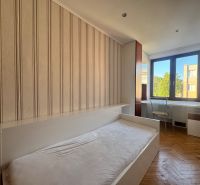 A bedroom in a 4-room apartment with a wood-patterned floor and a desk.
