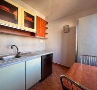 The kitchen of a 4-room apartment with a kitchen table, dishwasher, and cabinets with a wooden decor.