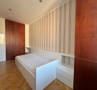 A bedroom in a 4-room apartment with a wood-patterned floor and built-in wardrobes.