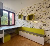 A room in a 4-room apartment with geometric wallpaper, furniture, and flooring with a wood decor.