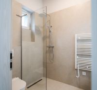 Bathroom in a 3-room apartment with an open shower and light tiles.