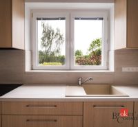 A kitchen in a 3-room apartment with a wooden decor floor and a view of the garden.