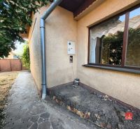 A family house in Ladice with a stone path along the wall and a garden.