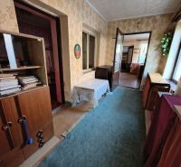 A hallway in a family house with a carpet, wooden furniture, and wallpapered walls.