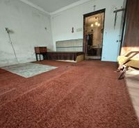 The interior of a family house with older furniture and a brown carpet.