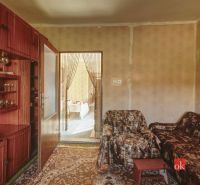 A room with a carpet, a sofa set, a glass cabinet, and a view into the adjacent room.