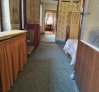 A hallway in a family house with a carpet and floral wallpaper.