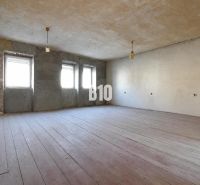 A spacious room with three windows and a wooden decor floor.