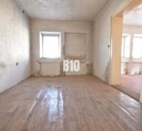 Room in a family house with a wooden decor floor and a damaged wall.