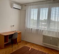 A room in a 2-room apartment with a desk, a chair, and air conditioning.