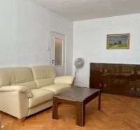 Living room with a cream sofa, wooden table, and a cabinet on the floor with a wooden decor.