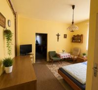 A room in a family house with wooden furniture, a carpet, and yellow walls.