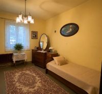 A room in a family house with carpeted flooring, yellow walls, a bed, and a mirror.
