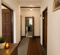 A hallway in a family house with a carpet runner, wooden furniture, and a decorative candle.