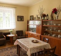 Traditional dining room in a family house with a display cabinet and a carpet on a wood-patterned floor.