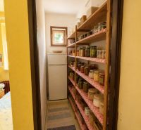 A pantry in a family house with shelves full of preserves and a window.