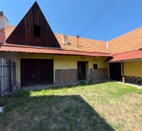 The courtyard of a family house in Dobrá Niva with a grassy area and a sloped roof.