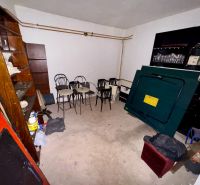 A basement in a family house with accumulated furniture and various items on a concrete floor.