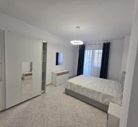 Bright bedroom with a bed, wardrobe, tiles, and curtains in a 2-room apartment.