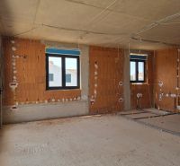 The interior of a 3-room apartment under construction with bare brick walls and plastic windows.