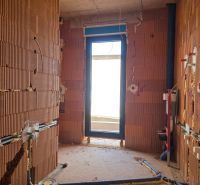 An unfinished room with raw brick walls and an exit to the balcony in a 3-room apartment.