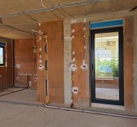 Under-construction 3-room apartment with brick walls and electrical installation prepared for assembly.