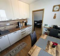 A kitchen with white cabinets and a wood-patterned floor in a 3-room apartment.