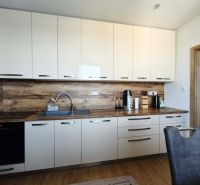A kitchen in a 3-room apartment with white cabinets and a wood-patterned floor.