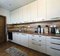 A kitchen in a 3-room apartment with white cabinets and a wood-patterned floor.