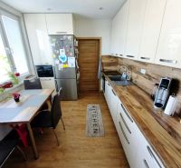 A kitchen in a 3-room apartment with a wood-decor floor, a table, and modern equipment.