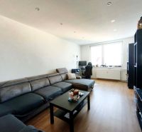 Living room in a 3-room apartment with a wooden decor floor, a sofa, and a PC desk.