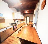 A kitchen in a cottage with a wooden decor floor, wooden ceiling, and dining table.