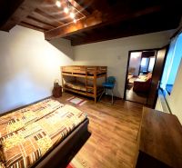 A room in a cabin with a bunk bed, a wooden decor floor, and ceiling beams.